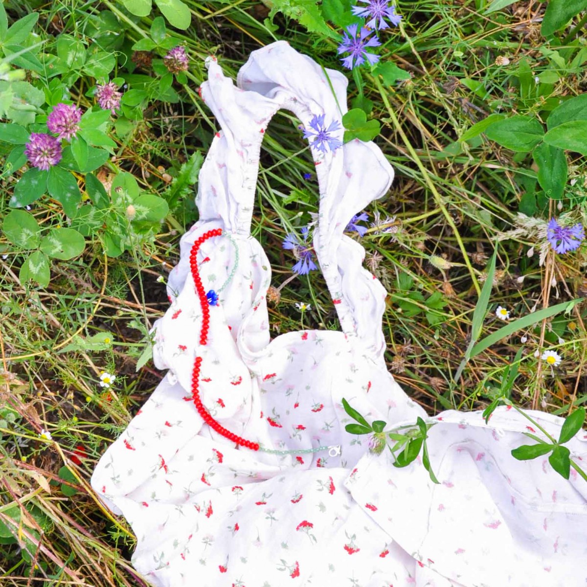 »Blumengarten« – Kette aus roten Edelsteinen und zweierlei Blüten: eine schimmernde Perlmuttblume in der Mitte und eine blaue Glasblüte an der Seite von pinapina