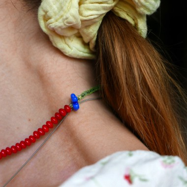 »Blumengarten« – Kette aus roten Edelsteinen und zweierlei Blüten: eine schimmernde Perlmuttblume in der Mitte und eine blaue Glasblüte an der Seite von pinapina